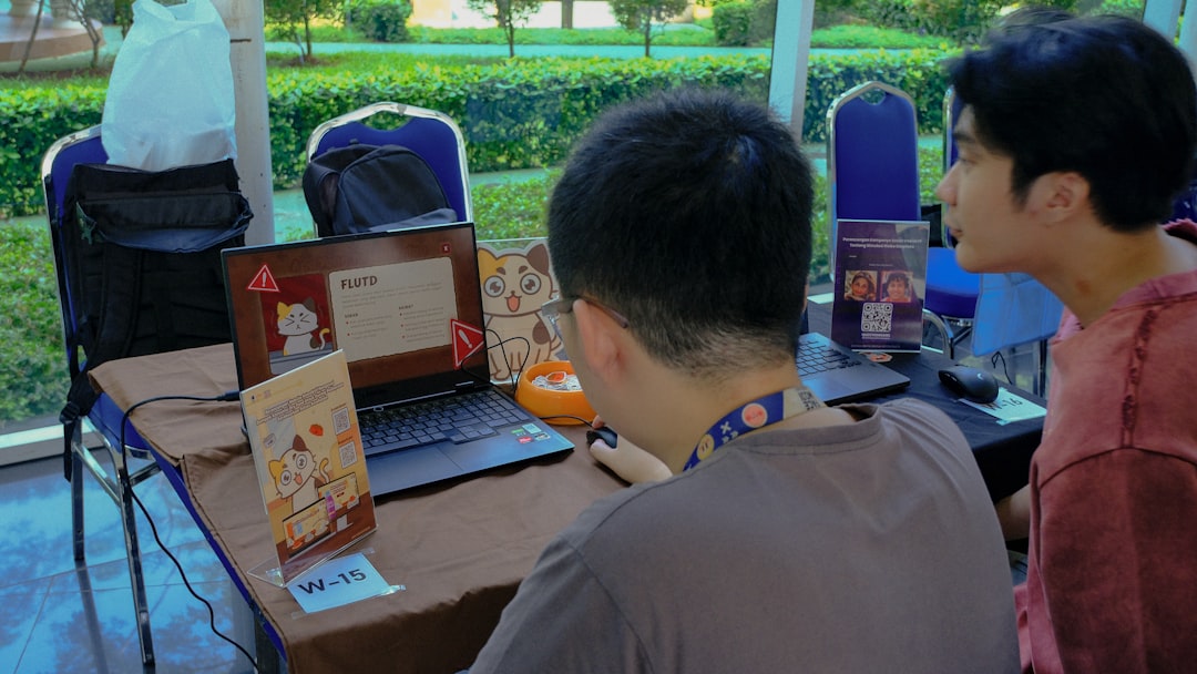 Two men looking at a laptop screen at a booth.