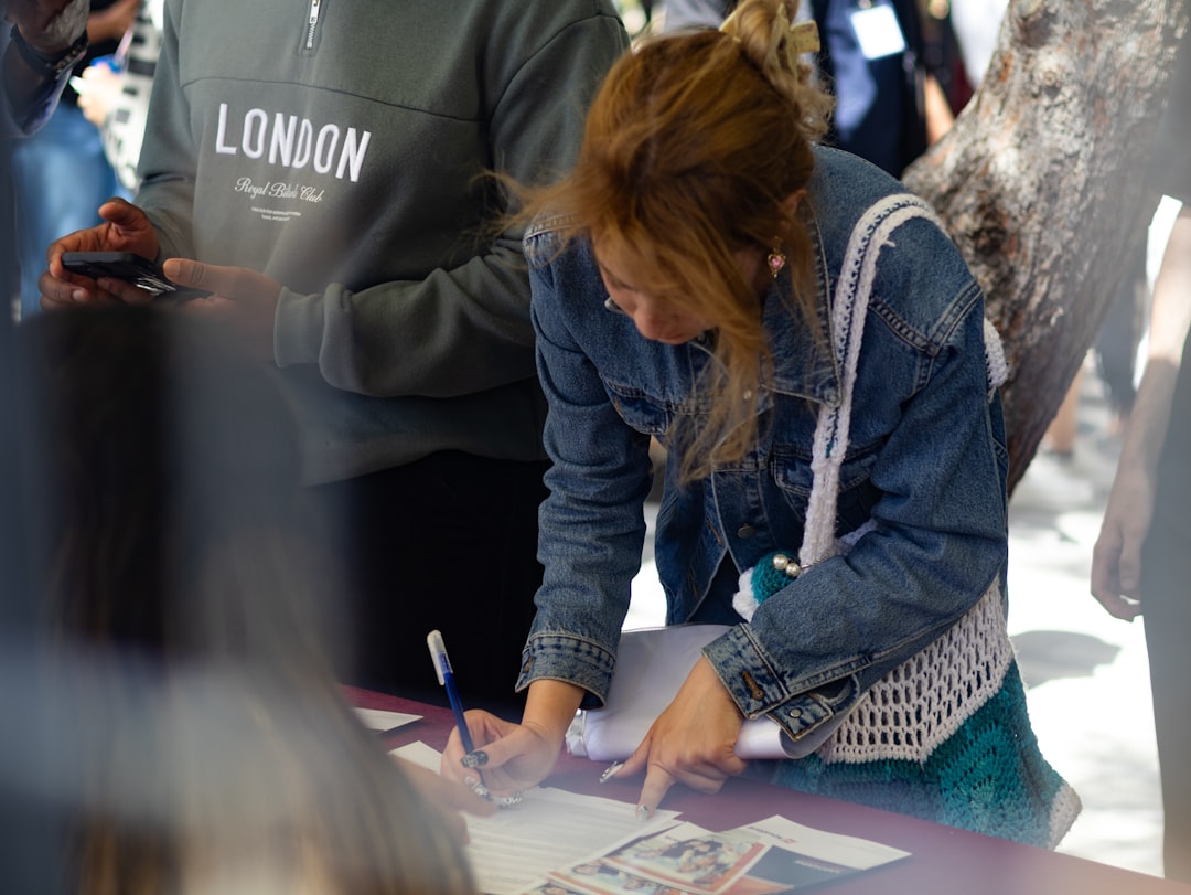 A woman signs a document at an outdoor event.