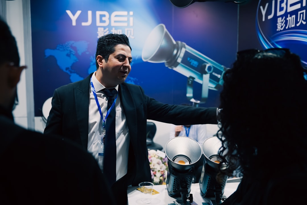 Man in suit presenting equipment at a trade show.